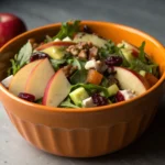 A close-up shot for Fall Apple Salad with visible orange internal ceramic bowl, with gray dramatic lighting