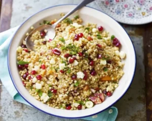 Quinoa Pasta Pomegranate Salad in a white bowl with a spoon on it