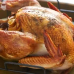 A perfectly roasted turkey garnished with herbs and spices, ready for Thanksgiving dinner.