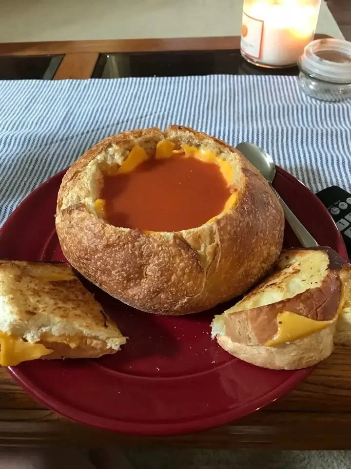 Grilled cheese sandwich served in a bread bowl with tomato soup