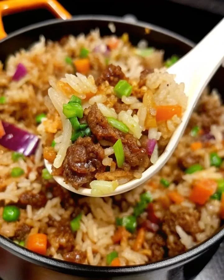 A delicious plate of onion beef fried rice garnished with fresh herbs.