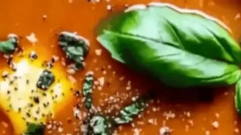 Bowl of cottage cheese tomato soup garnished with fresh herbs and spices.