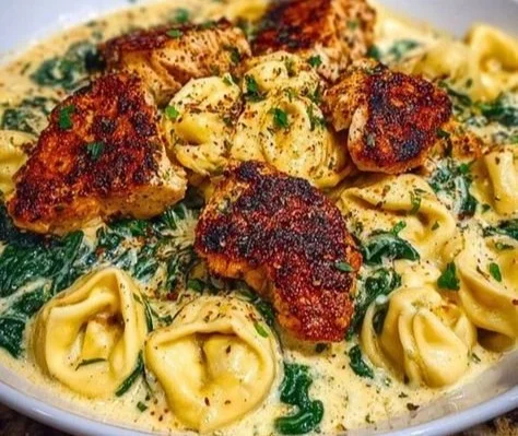 Creamy chicken tortellini served in a bowl with herbs