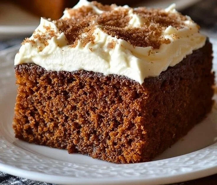 A slice of rich Gingerbread Cake topped with frosting and spices.