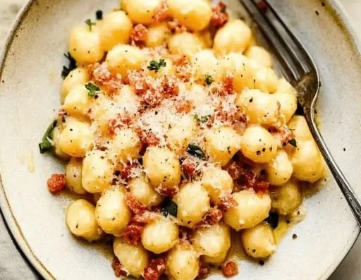 Delicious gnocchi carbonara with creamy sauce and pancetta garnished with herbs