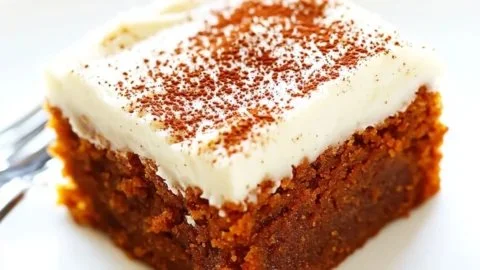 Delicious homemade pumpkin bars with creamy cheese frosting on a rustic wooden table.