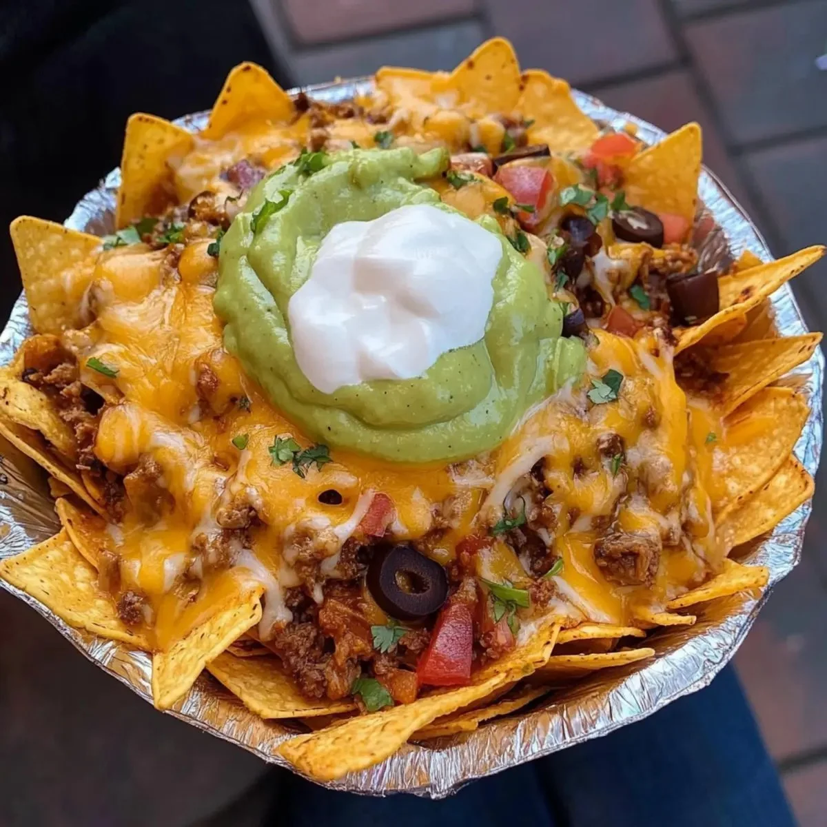 Plate of irresistibly cheesy nachos topped with jalapenos and guacamole.