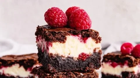 Raspberry Cheesecake Brownies topped with fresh raspberries and cream cheese frosting.