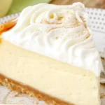 Delicious Eggnog Cheesecake topped with eggnog whipped cream and nutmeg.