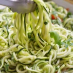 Delicious zucchini noodles topped with garlic, basil, and parmesan in a bowl.