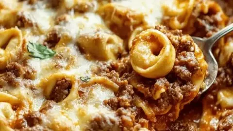 Baked Beefy Tortellini casserole topped with melted cheese and herbs