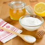 Ingredients for homemade baking soda face mask recipe, featuring yogurt, honey, lemon, and a wooden spoon for natural skincare.