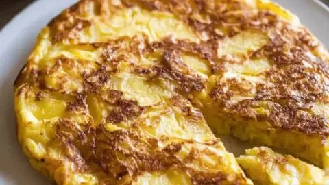 Delicious homemade Potato Omelette garnished with herbs in a skillet.