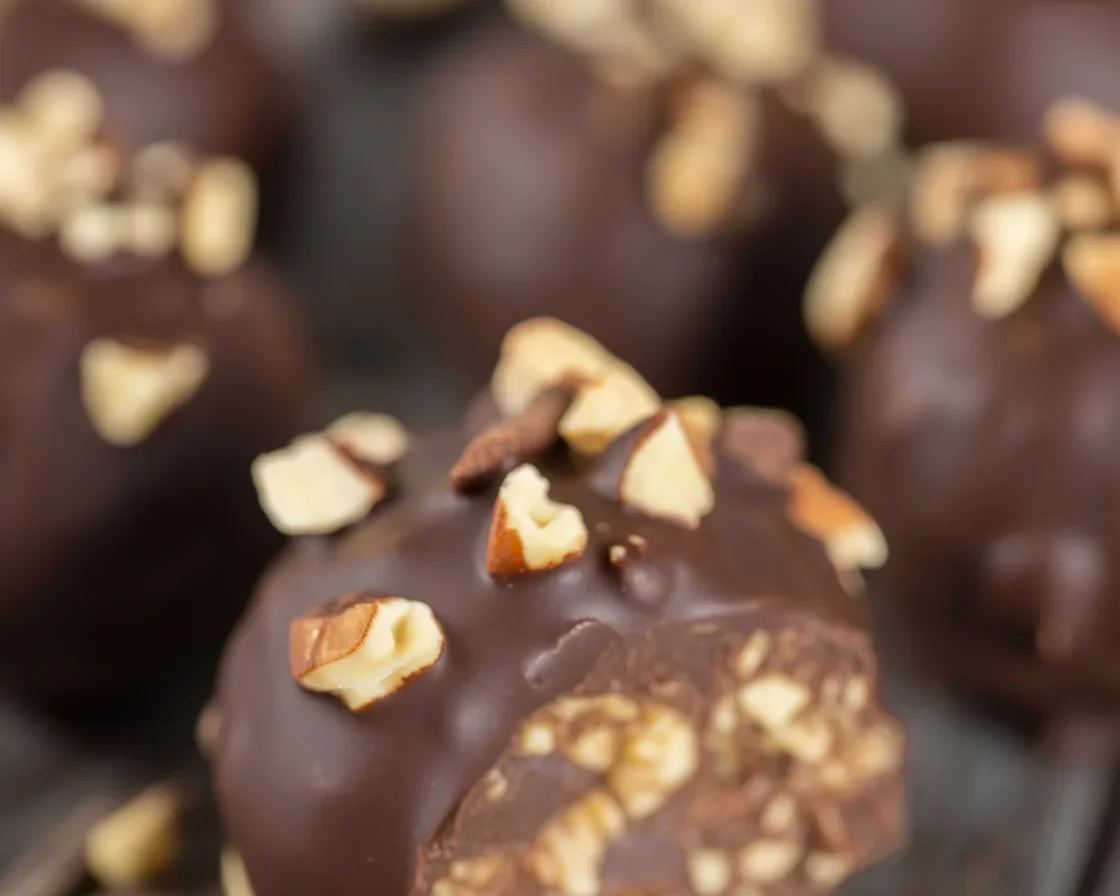 Pecan Pie Truffles coated in chocolate with chopped pecans on top