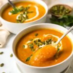 creamy cauliflower carrot soup in a white bowl