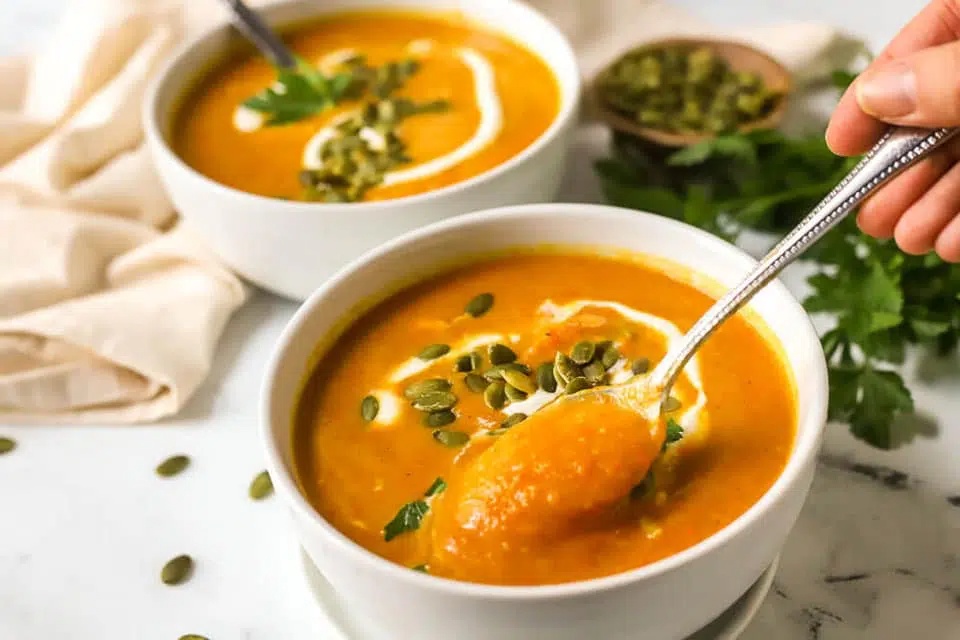 creamy cauliflower carrot soup in a white bowl