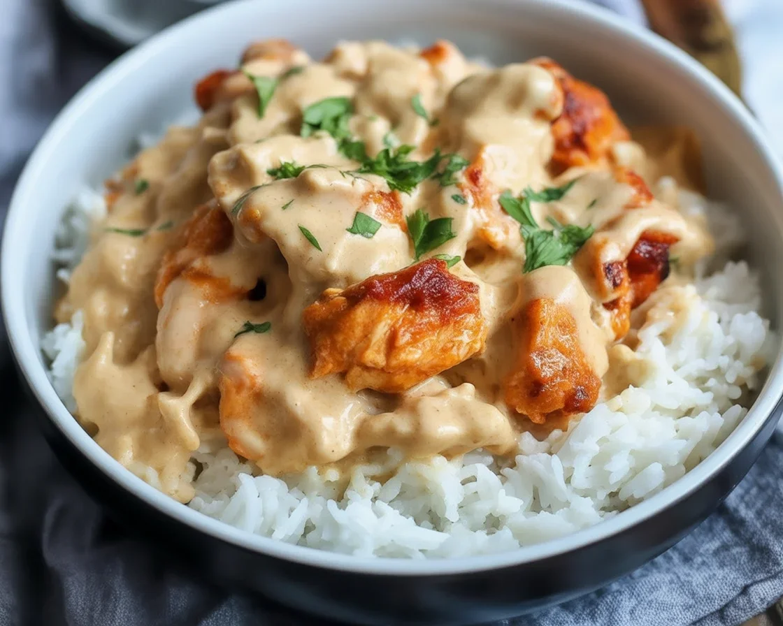 Delicious Creamy Smothered Chicken And Rice served on a plate with herbs.