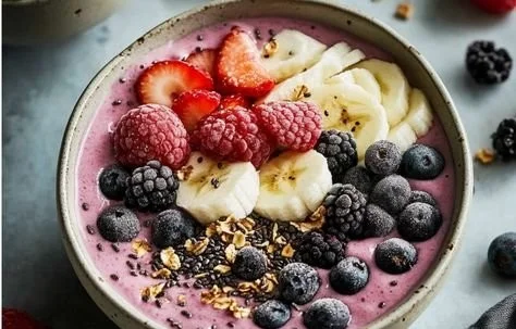 Colorful fruit protein smoothie bowl topped with fresh berries and seeds
