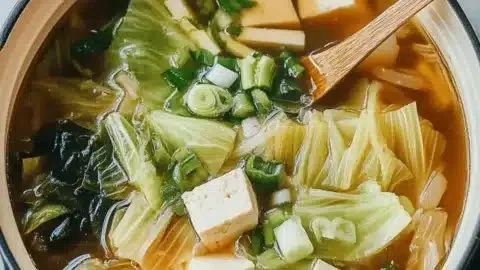 Bowl of Napa Cabbage Tofu Soup with fresh ingredients and herbs, perfect for comfort.