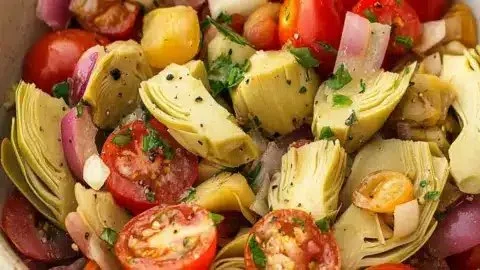 Fresh Tuscan Artichoke Tomato Salad garnished with herbs and olive oil