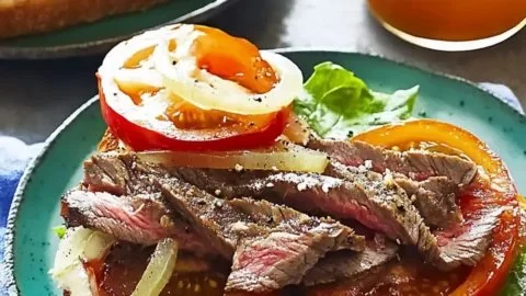Open sandwich with savory steak, tomato, and sweet onion