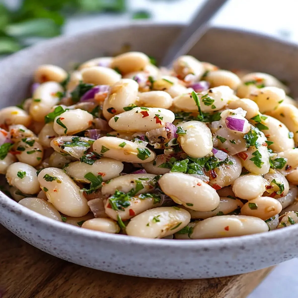 Zesty lemony white bean salad served in a bowl with fresh herbs.